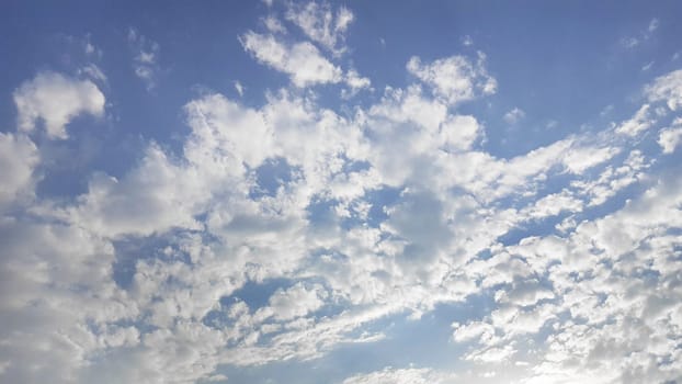 The azure sky, dotted with fluffy cumulus clouds, creates a picturesque natural landscape. The electric blue horizon meets the atmosphere in a stunning meteorological phenomenon