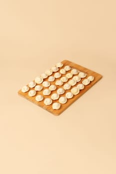Semi-finished raw dumplings lie neatly on a wooden board, copy space.