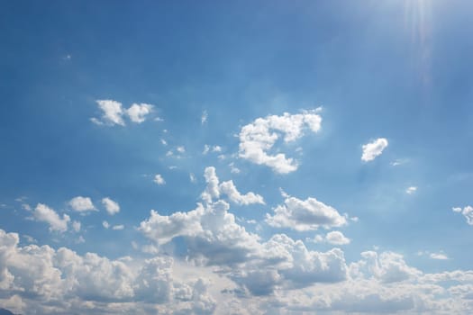 Summer sky is a canvas blue, dotted with fluffy white clouds. As the sun shines brightly, sky seems endless and serene, each cloud adding to the sky's tranquil beauty. Sky's vastness is calming.