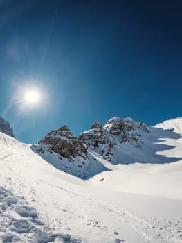Snow-capped high mountain pass: Three majestic rocky peaks, kissed by the winter sun, casting captivating shadows. Plenty of copy space in the vertical frame.