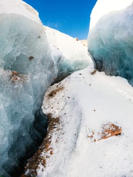 A stunning winter landscape on the way to Bogdanovich Glacier in Kazakhstan's Almaty Tian Shan Mountains. The path winds through a blue ice corridor adorned with mountain stones.