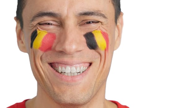 Close up of a man with a belgian flag painted on the face smiling at camera