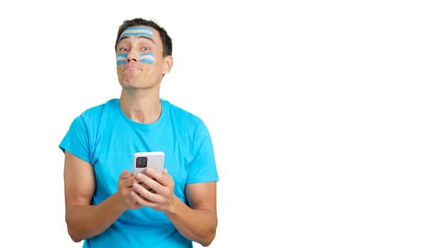 Argentina supporter with the flag of Argentina painted on his face, looking at his mobile phone smiling