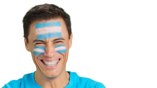 Close up of a man with a argentine flag painted on the face smiling at camera