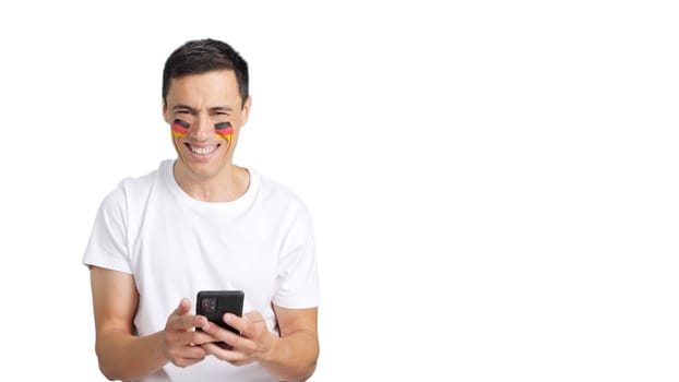 German man with the flag of Germany painted on his face, looking at his mobile phone smiling