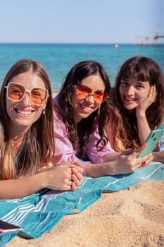 Group of smiling multiethnic women enjoying vacation. Beautiful and cheerful Gen Z girls with their mobile phones pose looking at the camera with a mobile phone.