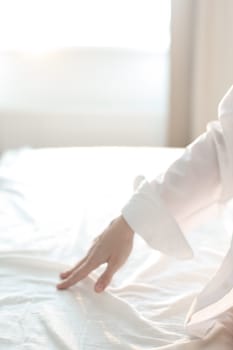 Woman Hand touching bed sheets, closeup. Young woman intimacy on bed. Soft, gentle, tender cozy morning concept