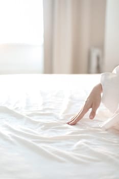 Woman Hand touching bed sheets, closeup. Young woman intimacy on bed. Soft, gentle, tender cozy morning concept