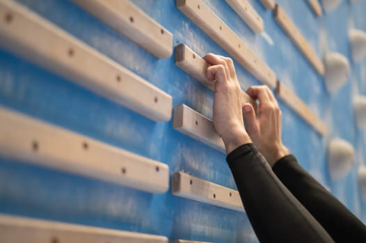 Caucasian man training his fingers on a wooden fingerboard in a rock climbing gym