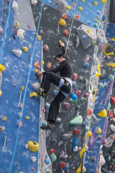 Caucasian man training on a climbing wall. Vertical photo