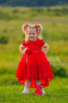 little girl in a red dress walks on the lawn