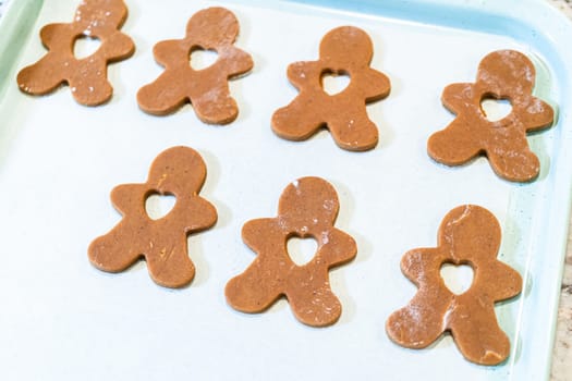 Gingerbread cookies, perfectly chilled and arranged on a baking sheet lined with parchment paper, await their turn to bake in the oven.