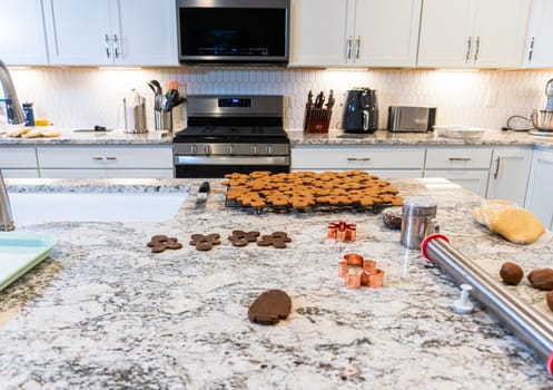 In a contemporary white kitchen, gingerbread cookie dough is skillfully rolled out, setting the stage for a delightful holiday treat.