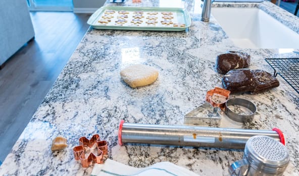 In a contemporary white kitchen, gingerbread cookie dough is skillfully rolled out, setting the stage for a delightful holiday treat.