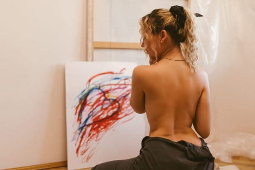 sexy artist paints on canvas with her back naked
