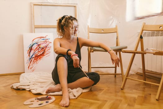 sexy artist paints on canvas with her back naked