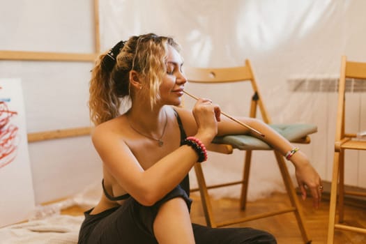 sexy artist paints on canvas with her back naked