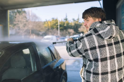 Cleaning car using active foam. Man washing his car on self car-washing