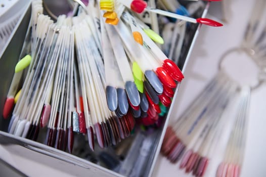 Close-up of colorful nail polish samples arranged in a box at a beauty salon, showcasing various shades for nail art and manicure.