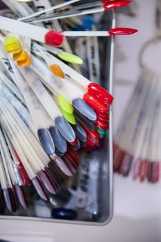 Close-up of various nail polish samples on display in a beauty salon, showcasing a range of vibrant colors and designs for manicure choices.