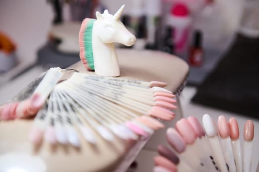 Close-up of various nail polish samples on display in a beauty salon, accompanied by a unicorn brush. Ideal image for beauty, manicure, and salon themes.