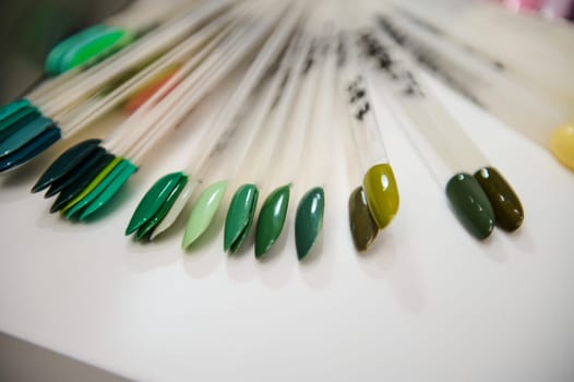 Close-up of assorted nail polish color samples at a beauty salon, showcasing various shades of green arranged neatly.