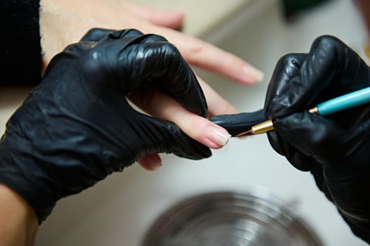 Close-up of a manicurist wearing black gloves, meticulously applying nail polish to a client's nails in a beauty salon. Perfect for concepts of care, beauty, precision, and professionalism.