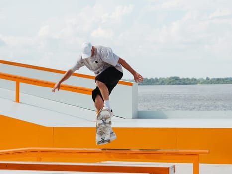 Caucasian Boy doing jump trick through rail on skateboard in skatepark. Professional sportsman jumping and doing trick on skateboard in outdoor park