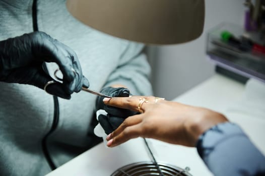 Professional manicure session at a beauty salon. A client receives expert nail care and grooming from a skilled technician wearing gloves.