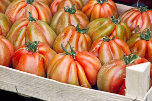 Fresh ribbed tomatoes in a wooden crate, perfect for vegetable and healthy food illustrations