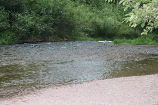 Waterfall stream close-up view from above clear flowing stream over ground gravel and stones. High quality photo