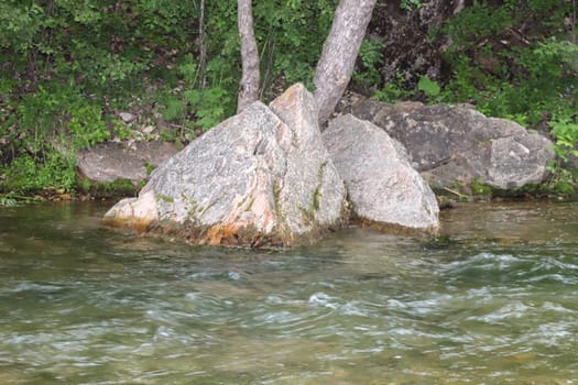 Waterfall stream close-up view from above clear flowing stream over ground gravel and stones. High quality photo