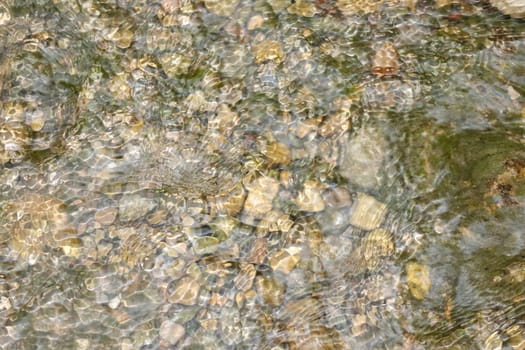 Waterfall stream close-up view from above clear flowing stream over ground gravel and stones. High quality photo