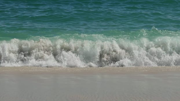Pristine white sand merges with the vibrant turquoise waves of a tranquil beach.