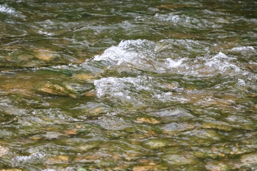 Waterfall stream close-up view from above clear flowing stream over ground gravel and stones. High quality photo