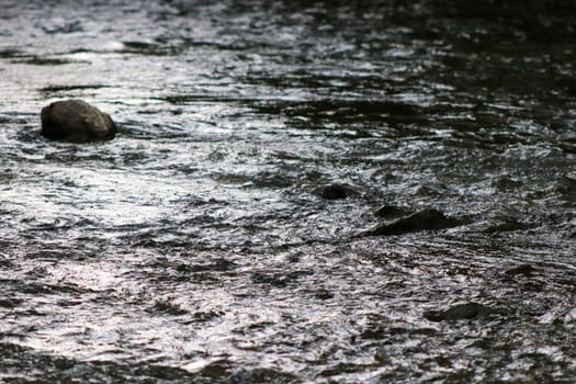 Waterfall stream close-up view from above clear flowing stream over ground gravel and stones. High quality photo