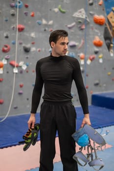 Portrait of a Caucasian man with a climbing harness in his hands in a climbing wall