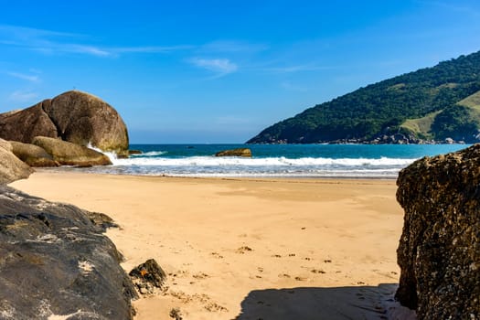 Bonete Beach on the island of Ilhabela seen through the rocks in the sand