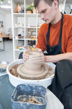 A potter works on a potter's wheel to smooth the surface of a vase