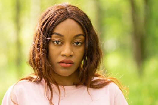 young black woman sitting on a bench in a park on a summer afternoon