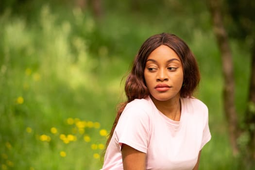 young black woman sitting on a bench in a park on a summer afternoon