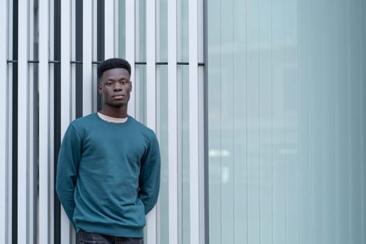 African man stands confidently in front of a towering skyscraper, looking up at its impressive height.