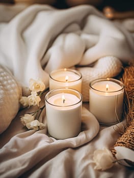 Three lit candles provide a serene ambiance among soft textiles and delicate white flowers, creating a peaceful and warm environment - Generative AI