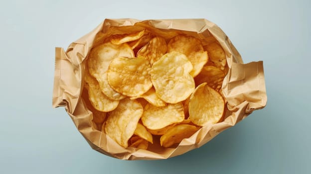 Crispy potato chips in a crinkled paper bag on a light blue background, close-up shot. Snack and junk food concept.