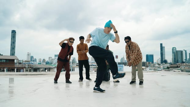 Professional break dance team practice B-boy dance while multicultural friends at rooftop. Young modern dancing group doing hip hop movement. Style,fashion,action. Outdoor sport 2024. Endeavor.