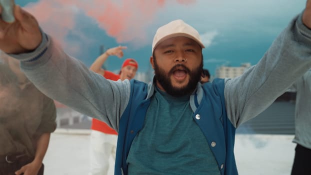 Group of multicultural hipster playing color flare at rooftop. Attractive street dancer holding colored smoke and perform break dance move to hip-hop music. Outdoor sport 2024. Endeavor.