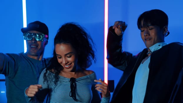 Happy hispanic girl with casual shirt dancing together with diverse break dancer with neon light. Professional street dancer moving to freestyle music with led light at house and party. Regalement.