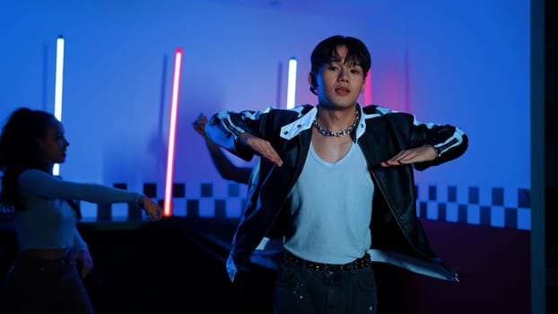 Skilled break dancer dancing in front of camera while diverse friend moving to pop or hip hop music behind. Attractive performer team taking turn to perform energetic movement at camera. Regalement.