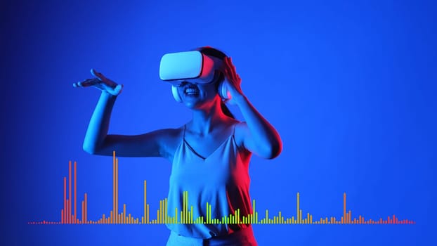 Smiling woman listening and dancing on fun song using VR headset with graphic equalizers electronic modern at studio dynamic lighting in music and technology concept blue background. Hallucination.