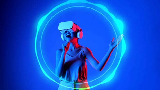 Woman singing song wearing VR headset with recording the music on circle graphic musical with neon lighting modern studio design at dynamic sound technology concept on blue background. Hallucination.